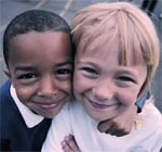 Black young child and a white young child in tight embrace